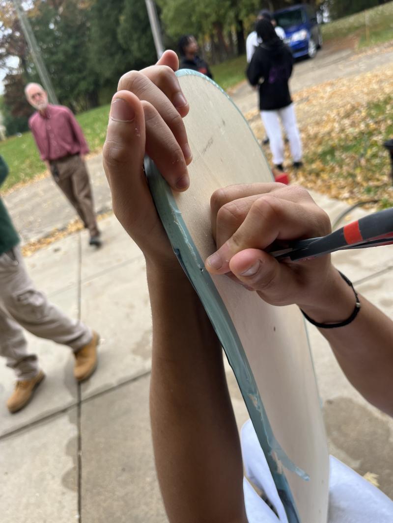 Picture of student preparing a skateboard deck before hydro-dipping w/Carlos Gacharna